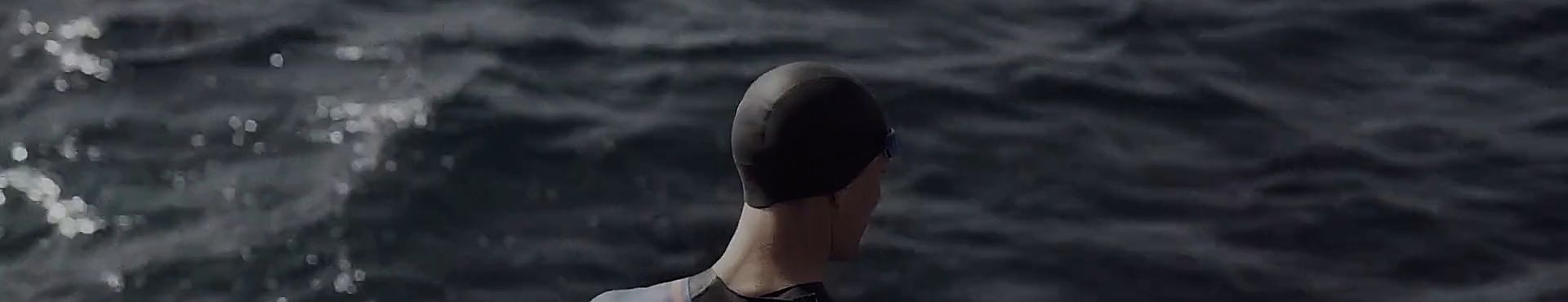 A swimmer in a wetsuit facing the ocean
